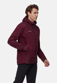 Giacca leggera bordeaux con cappuccio, chiusura con zip e due tasche frontali. Presenta un'area del petto texturizzata e polsini regolabili.