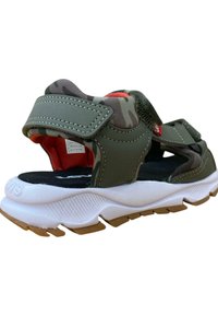 Sandalias de camuflaje verde con suela de goma, correas ajustables de Velcro y plantilla acolchada, con una prominente entresuela blanca y detalles texturizados.