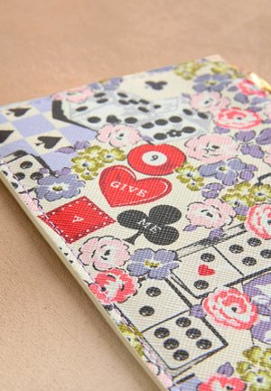 Notatnik z pokrywą z teksturowanej tkaniny, zdobiony florystycznym i gamingowym motywem w pastelowych kolorach, w tym sercami, kośćmi i geometrycznymi wzorami.