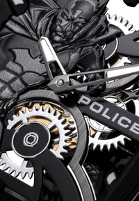 Melna un sudraba pulksteņa dizainā ir sarežģīti veidotas zobrati, izteikts Betmena tēls un gumijas siksniņa ar "POLICE" zīmolu.