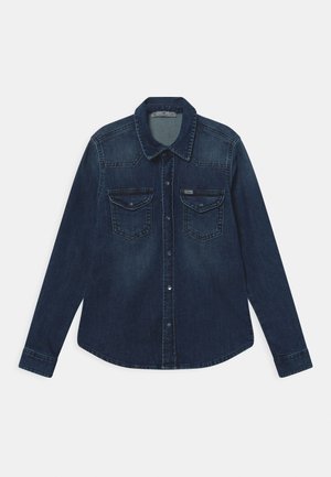 Dunkelblaues Jeanshemd mit langen Ärmeln, vorderer Knopfleiste und zwei Brustklappentaschen mit Knöpfen auf weißem Hintergrund.