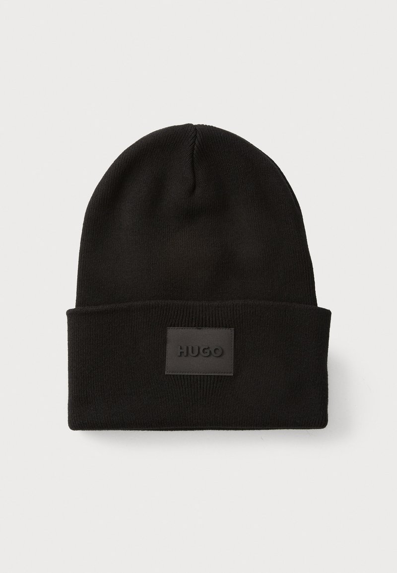 Black knit beanie with a folded cuff; features a rectangular black leather patch embossed with "HUGO" on the front. Soft texture.