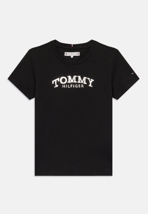 Zwarte katoenen t-shirt met een opvallend wit "TOMMY HILFIGER" logo in een gebogen ontwerp. Korte mouwen met een kleine driekleurige accent op de mouw.