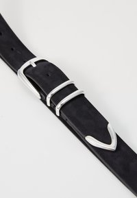 Cinturón de ante negro con una hebilla metálica plateada, que presenta una textura suave y elegante y tres púas para ajuste. Realzado con un detalle curvo.