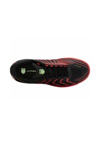 Chaussure de sport noire avec des accents rouges, tige texturée, motifs en zigzag et logo vert. Présente un design à lacets et une semelle rembourrée.