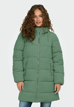 Manteau rembourré vert à texture côtelée, avec un col haut, une fermeture éclair et deux poches latérales. Manches longues et coupe mi-longue.