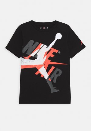 Sort t-shirt med stort hvidt og rødt Jumpman-silhuet, der overlapper grå og rød "Nike Air"-tekst foran.