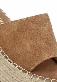 Sandalia deslizante de ante marrón con un upper ancho y suela de yute. Presenta un detalle de borde cosido y un acabado texturizado.