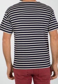 Navy and cream striped short-sleeve T-shirt with a relaxed fit, displayed from the back, paired with red pants.