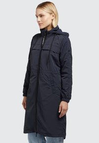 Giacca lunga navy in tessuto leggero con zip sul davanti, cappuccio regolabile, vita con coulisse e polsini elastici. Presenta tasche laterali.