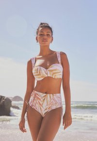 Bikini set met een roze basis en beige en gouden bladdesigns. De top heeft een hartvormige halslijn en brede banden; de onderkant is hoog uitgesneden met zijstrikken.