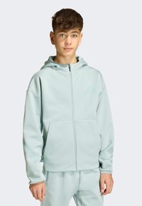 Chaqueta con capucha en verde menta claro, con cremallera, confeccionada en un material suave, con un bolsillo delantero y un detalle de logo sutil en el pecho.