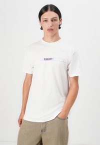 Hvit bomulls-T-skjorte med en grafisk logo i lilla og blått midt på brystet. Korte ermer, rund hals, løs passform.