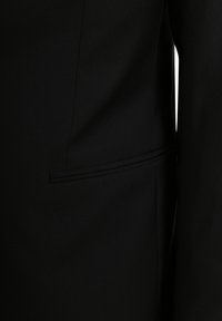 Zwarte op maat gemaakte blazer met een zachte stofstructuur, gestructureerd ontwerp en een zijzak met een subtiele biesdetail.