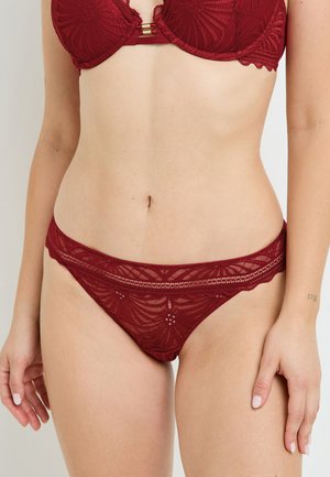 Reggiseno in pizzo bordeaux con ferretto, caratterizzato da un bordo ondulato e un motivo floreale; perizoma trasparente abbinato con dettagli intricati e vita bassa.