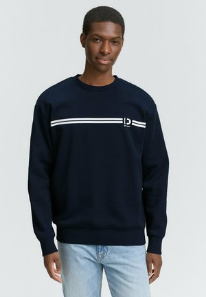 Navyblauwe sweatshirt van zacht materiaal, met een witte horizontale streep en logo op de voorkant, voorzien van ribgebreide manchetten en een halslijn.