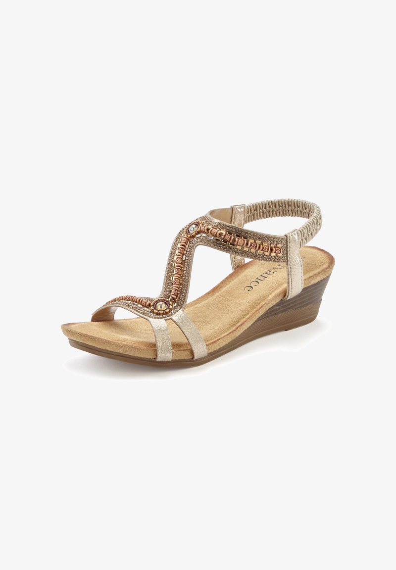 Beige Keilabsatzsandale mit komplexen Perlen- und Stickdetails an der Oberseite. Weiches Fußbett, elastischer Fersenriemen und leicht strukturierte Sohle.