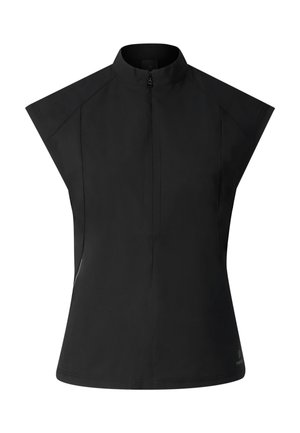 Kvinde iført sort ærmeløs top med lynlås, sorte shorts, sort kasket, solbriller og sorte sandaler, står med front mod kameraet på hvid baggrund.