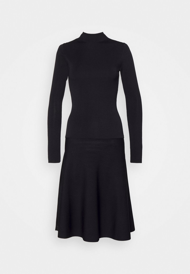 Haut noir ajusté à manches longues avec col montant, associé à une jupe midi noire évasée, sur fond blanc uni.