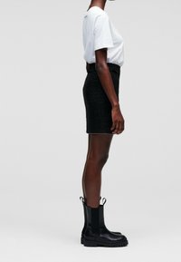 Black tweed skirt with a fitted silhouette, paired with a white t-shirt, and black ankle boots featuring elastic side panels.