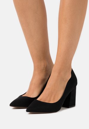 Décolleté neri in suede con punte affusolate e tacco a blocco spesso. Texture liscia e design minimalista; nessun motivo o accento visibile.