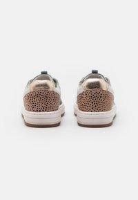Sneakers con una parte superiore bianca e azzurra chiara, dettagli in rosa metallico, e un cappuccio per il tallone perforato marrone testurizzato su una suola bianca.