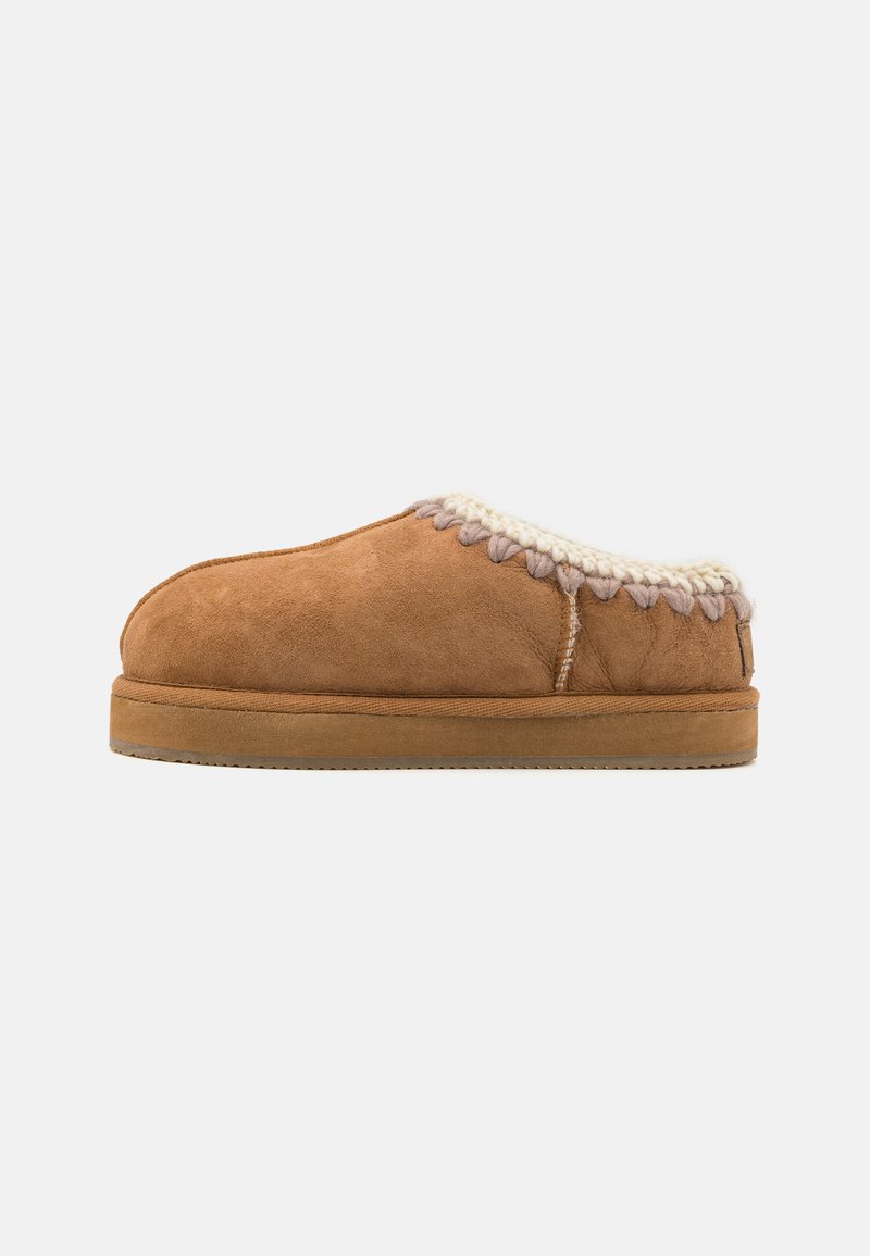 Pantofola in suede marrone con una morbida fodera in shearling color crema e cuciture decorative attorno all'apertura. Suola in gomma a profilo basso.