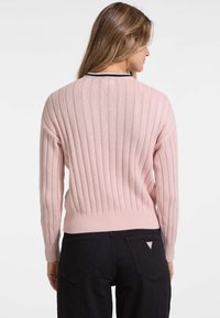 Ljusrosa ribbad tröja med långa ärmar, med svart kantning längs kragen. Tyget är mjukt med en figurnära design.