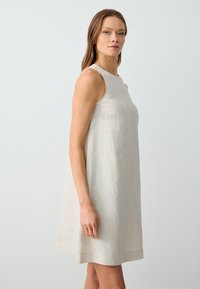 Ärmelloses beiges Leinenkleid mit einer lockeren A-Linie, das eine glatte Textur und einen geraden Saum hat.