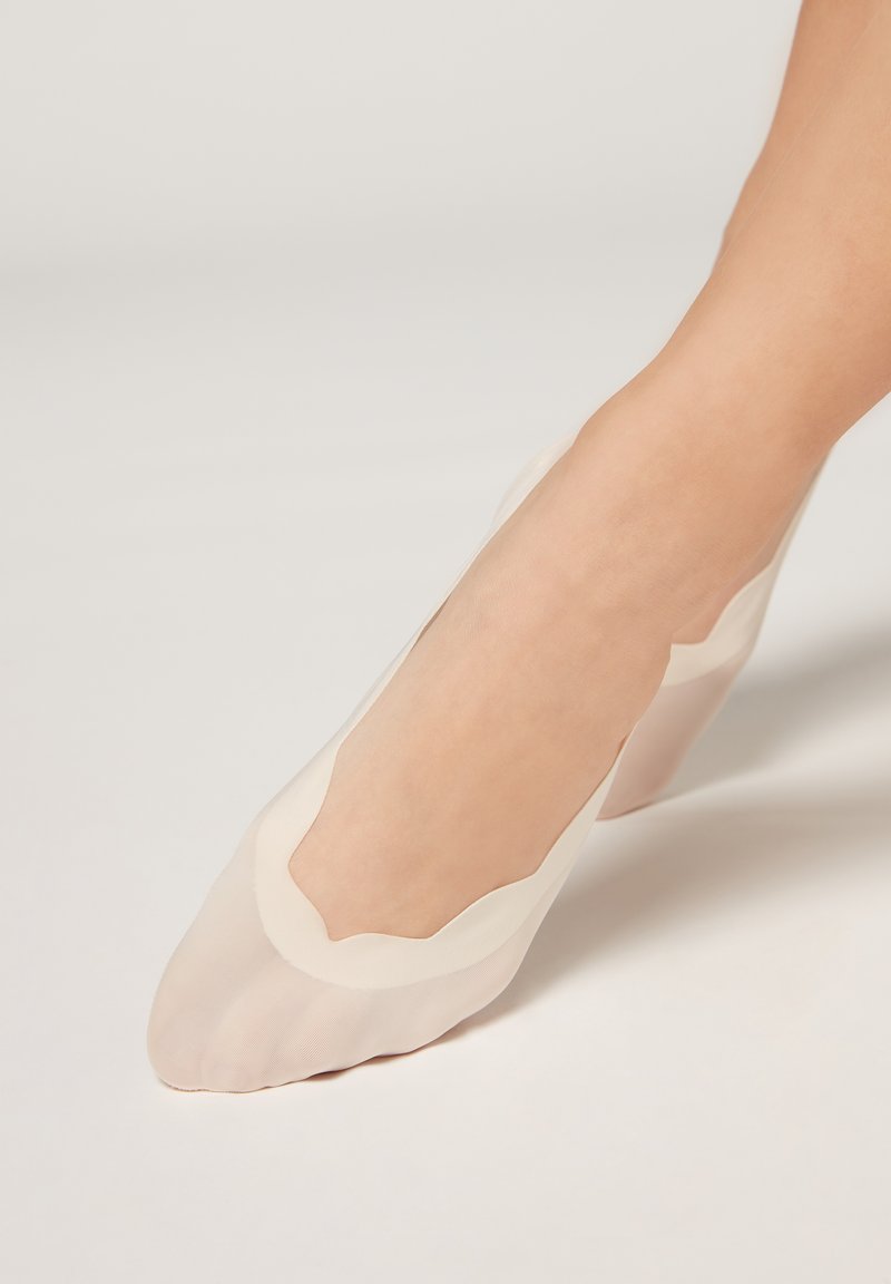 Bailarinas nude transparentes con un diseño en ondas y una textura suave, que presentan un perfil bajo que resalta el pie.