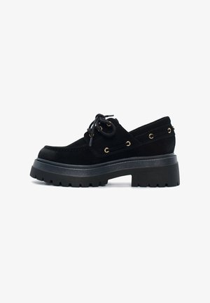 Scarpa nera in suede con lacci, punta rotonda, suola a piattaforma spessa e occhielli dorati. Presenta un design testurizzato, profilo basso e accenti laterali.