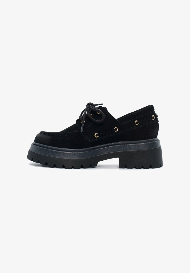 Scarpa nera in suede con lacci, punta rotonda, suola a piattaforma spessa e occhielli dorati. Presenta un design testurizzato, profilo basso e accenti laterali.
