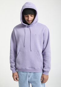 Hoodie violet clair en mélange de coton, avec une poche kangourou, une capuche avec cordon de serrage et des poignets côtelés, associé à un jean en denim clair.