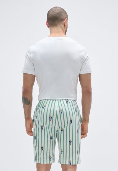 Λευκό κοντομάνικο μπλουζάκι συνδυασμένο με σορτς με πράσινες και λευκές ρίγες που φέρει εκτύπωση με χαρακτήρα καρτούν. Επίπεδη μέση και εφαρμογή μέχρι το γόνατο.
