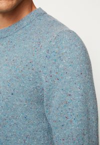 Pullover aus strukturiertem blauen Strickmaterial mit mehrfarbigen Sprenkeln. Verfügt über einen Rundhalsausschnitt und gerippte Bündchen.