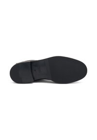 Suela de zapato de cuero negro con una superficie lisa y texturizada, y pequeñas ranuras cerca del tacón. Presenta la marca y detalles de tamaño.
