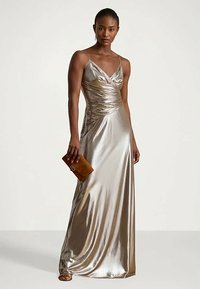 Metalni zlatni večernji haljina s uskim, naboranim korzetom i tankim trakicama, uparen s malom smešnom torbicom.