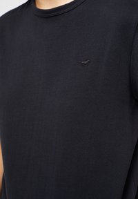 T-shirt nera a maniche corte in morbido cotone con scollatura rotonda, caratterizzata da un piccolo logo a forma di cavallo ricamato in nero sul petto.