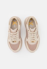 Beige athletic shoes with mesh and suede upper, round toe, beige laces, logo accents, and a textured rubber sole.