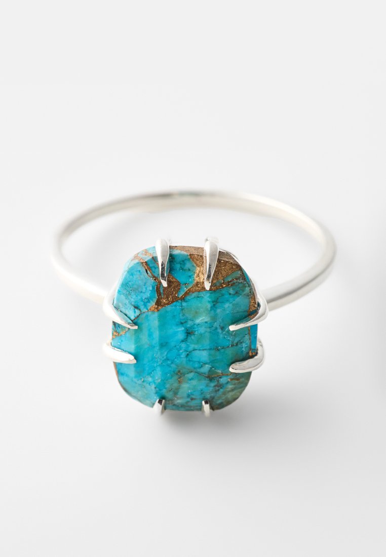 Anillo de piedra turquesa con una gran gema de turquesa de forma irregular, engastada en garras de plata sobre una delgada banda de plata.