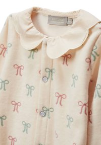 Une combinaison en polaire rose clair dotée d'un col Peter Pan, de boutons-pression argentés et d'un motif de nœuds verts et roses.