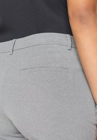 Γκρι παντελόνια από ελαστικό ύφασμα με λείο τελείωμα, διαθέτουν στενή ζώνη και μία μόνο πίσω τσέπη με διακριτικές λεπτομέρειες στην ραφή.