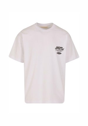 T-shirt bianco in cotone con maniche corte, scollatura a girocollo e logo testuale nero sul lato sinistro del petto. Design semplice, orlo dritto, texture morbida.