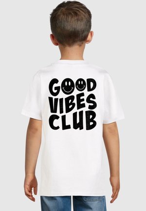 T-shirt bianco in cotone con bold testo nero "GOOD VIBES CLUB" e faccine sorridenti, maniche corte e scollatura a girocollo.