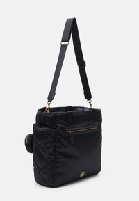 Svart nylontote med ett justerbart axelband, framficka med dragkedja, kviltad sidtextur och detaljer i guld.