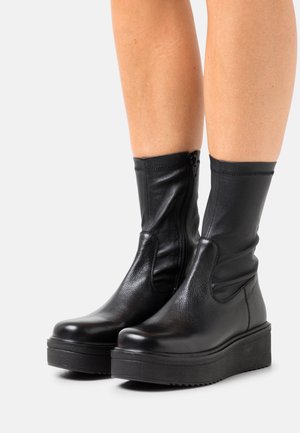Black leather ankle boots with a soft, textured finish. Features a side zipper, rounded toe, and a thick, flat rubber sole.