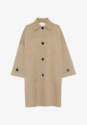 Jachetă oversized bej cu un guler ascuțit, închidere frontala cu nasturi și buzunare mari aplicate. Are nasturi negri și o textură netedă.