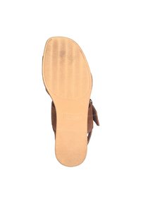 Chaussure en daim marron avec une semelle en caoutchouc texturé brun clair. Présente une finition lisse et une légère courbure dans sa forme, avec le logo de la marque visible sur la semelle.