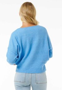 Jasnoniebieski, oversize'owy sweter z szerokim dekoltem i opuszczonymi ramionami. Miękka, dzianinowa tekstura z prążkowanymi mankietami i wykończeniem u dołu.