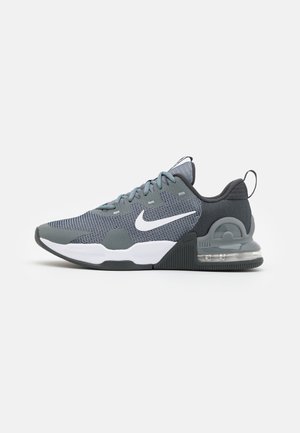 Grijze en zwarte Nike sportieve sneaker met wit swoosh-logo, mesh bovenwerk, dempende zool en zichtbare luchtunit in de hiel, op een witte achtergrond.